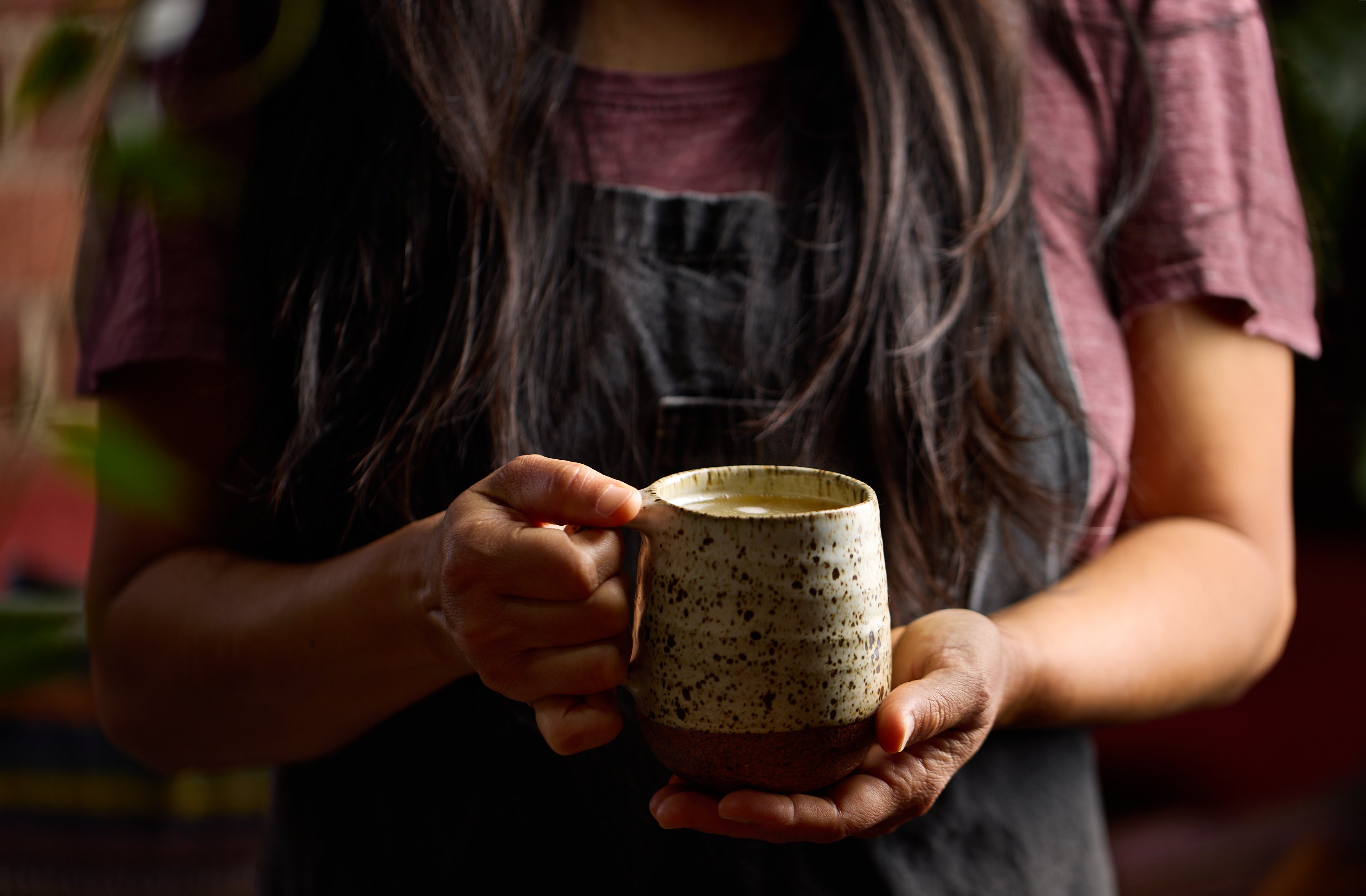 Hands holding a warm handmade ceramic mug of Mama Tong bone broth
